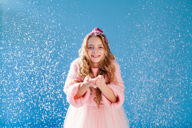 漂亮的女孩戴着帽子，穿着暖和的衣服玩雪图片下载