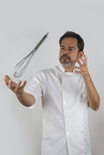 糕点师像魔术师一样让搅拌器悬浮在白色背景上。图片下载