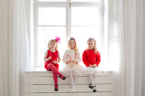 三个穿着红色和白色衣服的小女孩坐在窗边图片下载