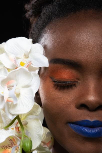 开朗的年轻非洲女人与橙色的花化妆。图片下载
