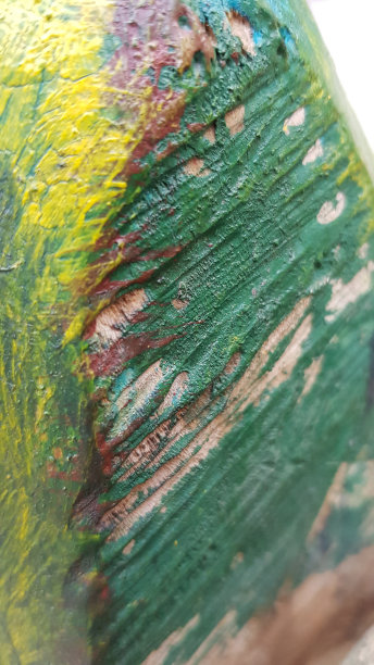 手工雕刻的木头表面，涂上绿色和黄色的油漆。柔软的焦点，以肋木纹理。木工行业背景摘要。图片下载