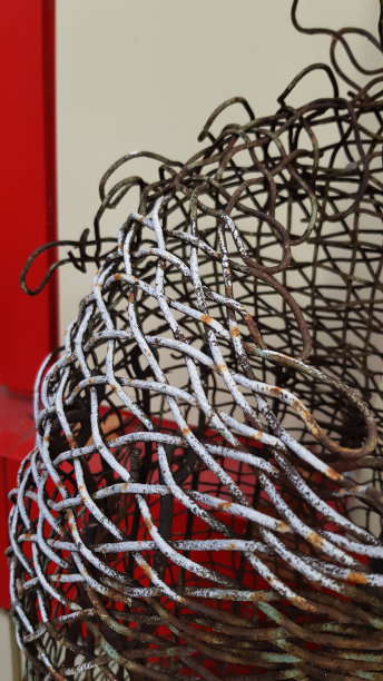 缠结生锈的金属丝网纹理特写在墙上的背景用红线。皱褶金属网，链环结构。工业枯燥乏味的背景。图片下载