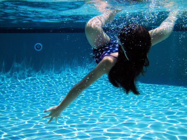 快乐的小女孩在游泳池里游泳图片下载