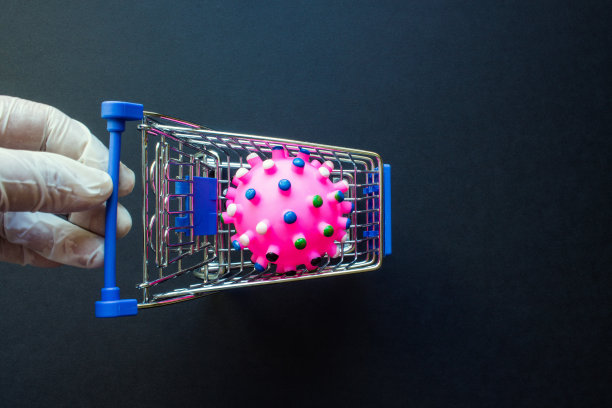 金属购物篮里的粉色冠状病毒分子，一只戴着白色橡胶手套的手图片下载