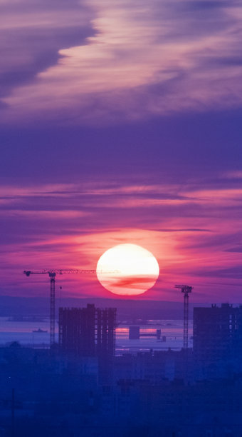 塔吊，在城市的一个建筑工地上建造一个新的高层公寓楼的日落或日出。有利可图的投资和改造项目，发展，纵向拍摄图片下载