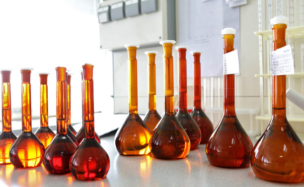在实验室里进行化学实验装有化学试剂的彩色烧瓶。科学家手中拿着许多玻璃药瓶。漂亮的显色试剂溶液。黄色和棕色的试管图片下载