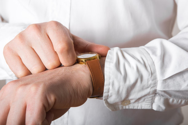 商人的近距离看手表在他的手上自由的空间。穿白衬衫的男人戴着豪华手表看时间。新郎婚礼准备。图片下载