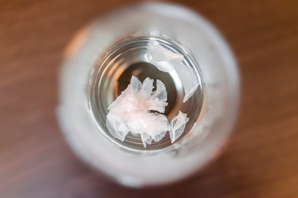 传统的日本粉白色盐渍樱花平顶视图以上浮动在茶水近距离与浅景深的木桌图片下载