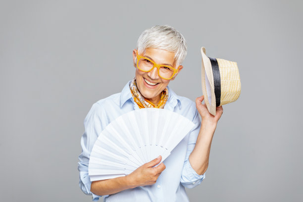 快乐的妇女与白色扇子和帽子在灰色的背景。图片下载