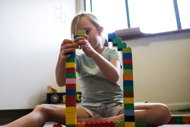 年轻的金发女孩在她的房间里玩积木图片下载
