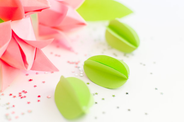 手工纸绿色的鸡蛋和粉红色的折纸郁金香映衬着银色的星星。复活节快乐背景。DIY的概念。图片下载