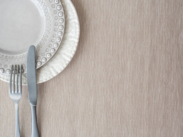 米色餐垫上的盘子和老式餐具。图片下载