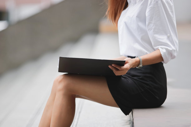 裁剪的图像年轻的商业女性与文件文件夹的工作在办公室外。图片下载