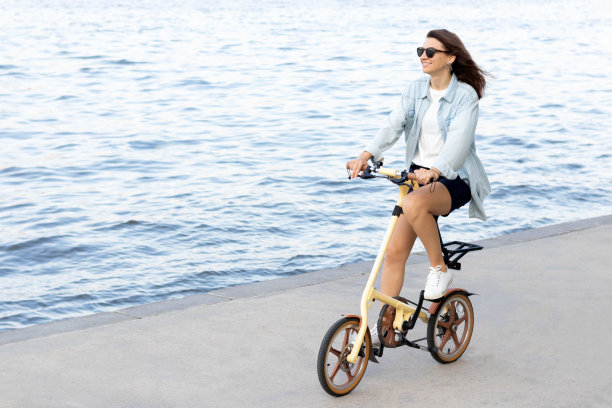 快乐的年轻女子在午后沿水泥路骑自行车图片下载