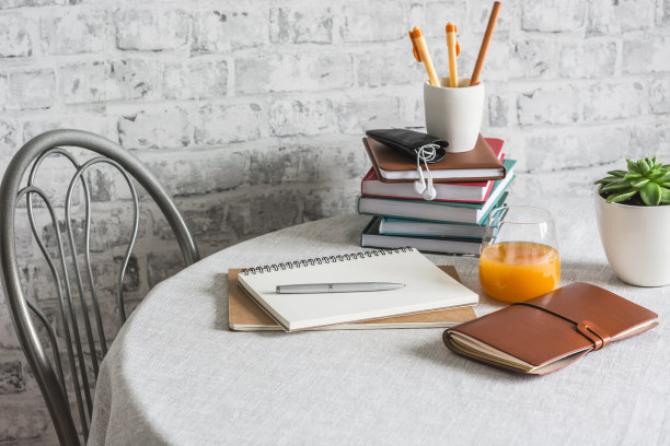 在线学习的概念。在一间明亮的房间里，书，课本，笔记本，一杯橙汁，鲜花放在家里的桌子上。远程学习图片下载