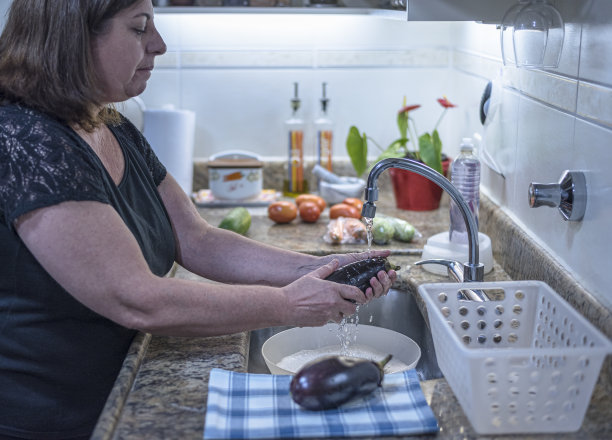 成年妇女在家庭厨房里洗蔬菜，然后把它们放进冰箱图片下载
