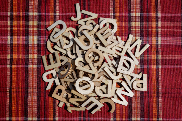 红色纺织材料上的一组混合木质字母，带有彩色条纹，俯视图，平铺图片下载