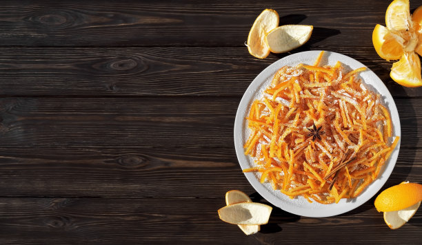 糖橙皮是儿童和成人的最爱。深色木桌上自制的蜜饯橘子皮和橘子皮。俯视图，复制空间图片下载