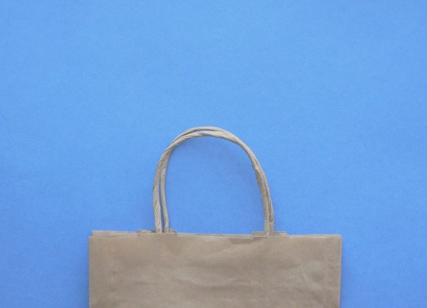模型的棕色牛皮纸包装与处理，空白工艺购物袋与区域为您的标志或文本，食品交付概念。安全的送货上门。蓝色背景与复制空间。图片下载