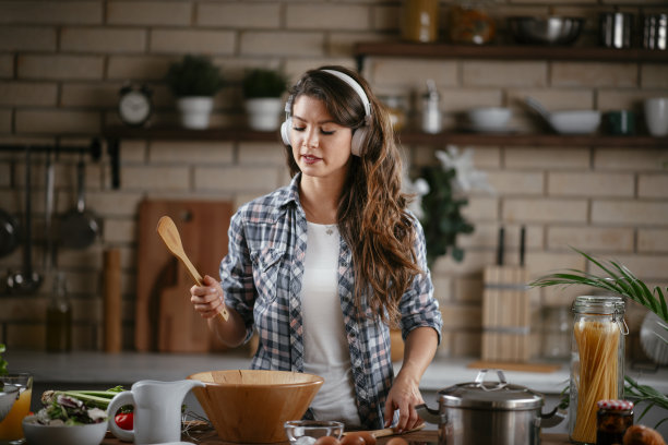 年轻女子在厨房里准备食物和听音乐图片下载