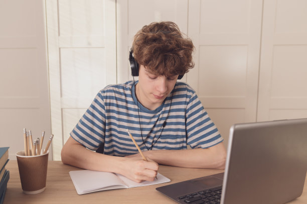 一个善于思考的孩子坐在他的书桌前想着学习。远程学习因为冠状病毒疫情图片下载