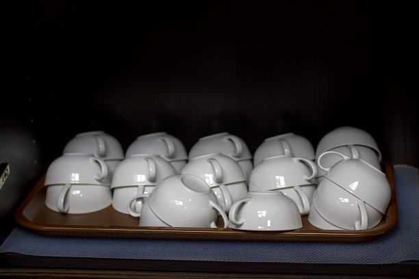 白色的咖啡杯，放在壁橱的架子上，背景是黑色的图片下载