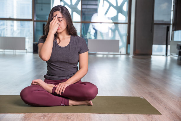 年轻女子在室内练习瑜伽的照片。美丽的女孩在课堂上练习瑜伽。瑜伽老师。模糊的背景图片下载