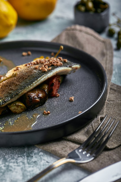 烤鲈鱼配茄子和酸橙。水平俯视图，俯视图。复制空间，灰色的混凝土大理石背景，柔和的光线。食品时尚照片图片下载