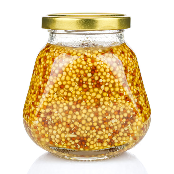 法国芥末在一个金字塔透明玻璃罐与封闭的镀金金属盖隔离在白色背景图片下载