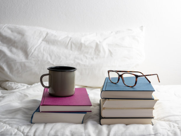 床上放着一堆书，还有一杯咖啡和老花镜图片下载