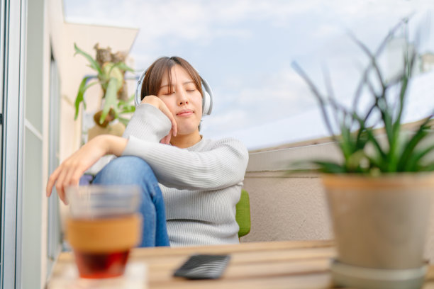 年轻女子在家阳台听音乐放松图片下载