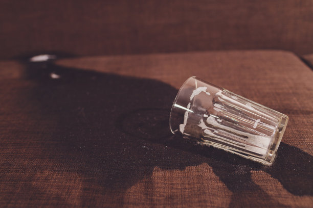 家庭酗酒。啤酒瓶和洒在沙发上的啤酒。图片下载