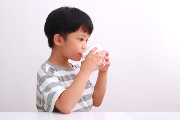 可爱的男孩拿着牛奶杯在白色的背景图片下载