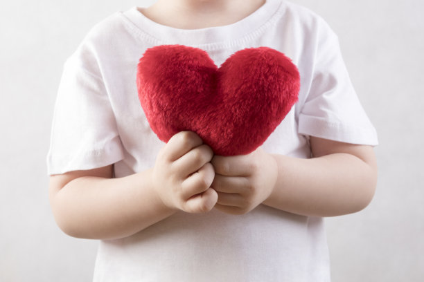 一个三岁的孩子，手里拿着一颗毛茸茸的红心图片下载