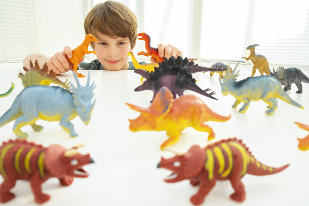 一个白人男孩在玩玩具恐龙图片下载