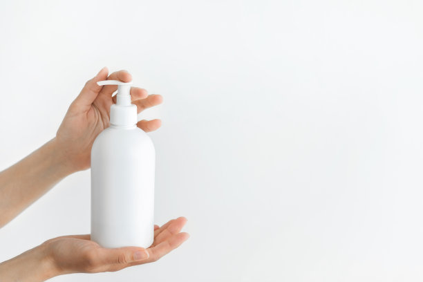 女人手持消毒剂的分配器。冠状病毒和感染的卫生预防。白色塑料瓶中的消毒剂。图片下载