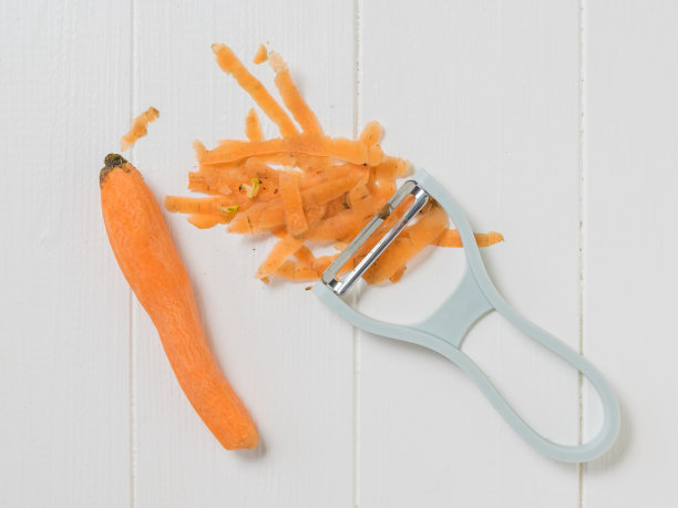 木桌上放着削皮刀和胡萝卜皮。图片下载