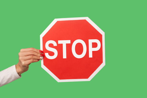 女性手握八角形红色停车交通标志的特写，标志着安全过马路，禁止和禁止图片下载