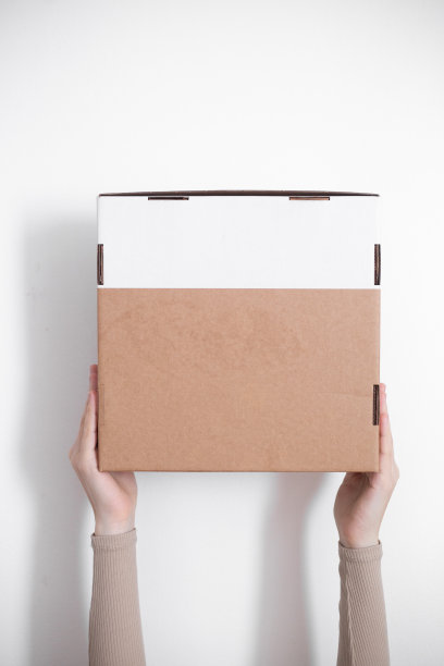 一个包裹纸箱在一个送货员的手在一个白色的背景。送货服务的概念。图片下载