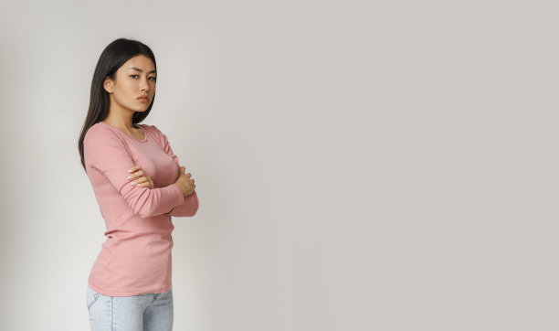 愤怒的亚洲女孩看着相机在灰色的背景图片下载