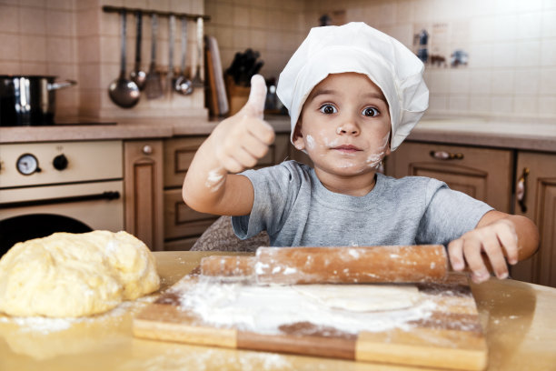一个小男孩帮助妈妈做披萨。幸福的家庭妈妈和孩子在周末早上在家。准备烤复活节蛋糕的生面团素材图片