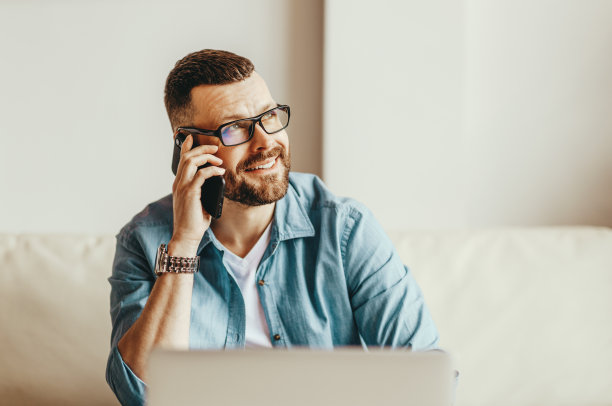 年轻的自由职业者，一边工作一边在家里用电脑打电话图片下载