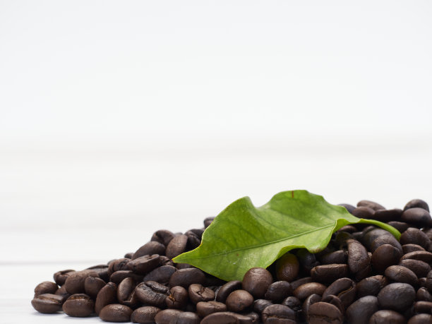 白木头上放着新鲜的咖啡豆和咖啡叶子。图片下载