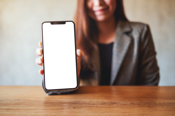 一名亚洲女商人在咖啡馆里拿着一部黑色手机，屏幕上是空白的图片下载