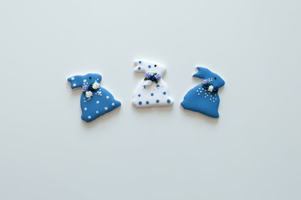 复活节上釉的兔子形状的饼干在白色的背景。复活节快乐的背景与彩色复活节饼干-兔子和花。桌上放着春天的花和复活节的姜饼和兔子。图片下载