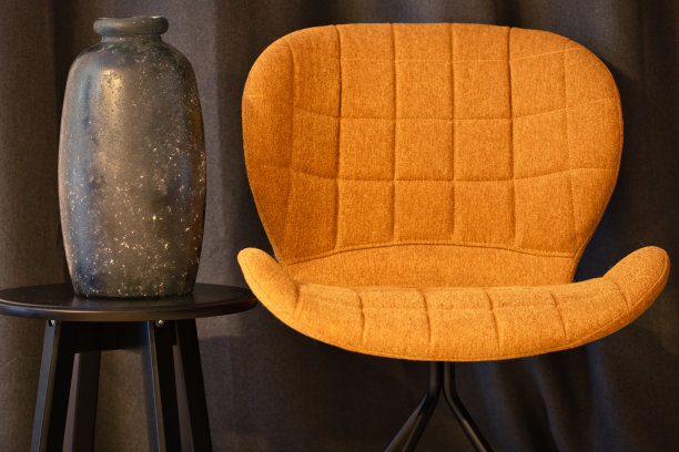 黑屋子里的橘色椅子。深色窗帘和空花瓶。图片下载