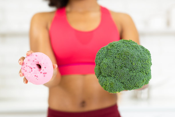 Fit Afro女孩拿着花椰菜和甜甜圈图片下载