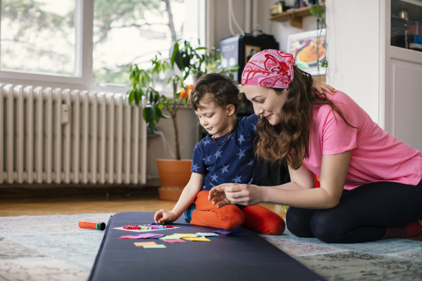 年轻的母亲和孩子一起在家制作纸手工艺品图片下载
