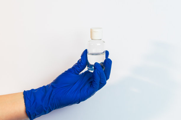 一只戴着蓝色乳胶手套的手拿着消毒剂。预防防范冠状病毒的概念。图片下载