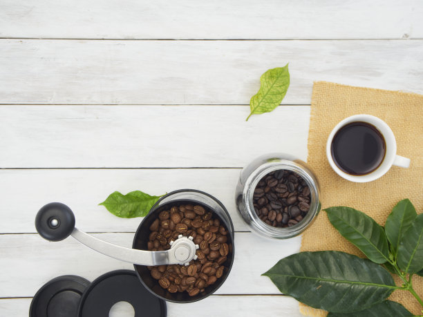 咖啡研磨机配咖啡豆，新鲜的咖啡叶放在旧的白木头上。图片下载